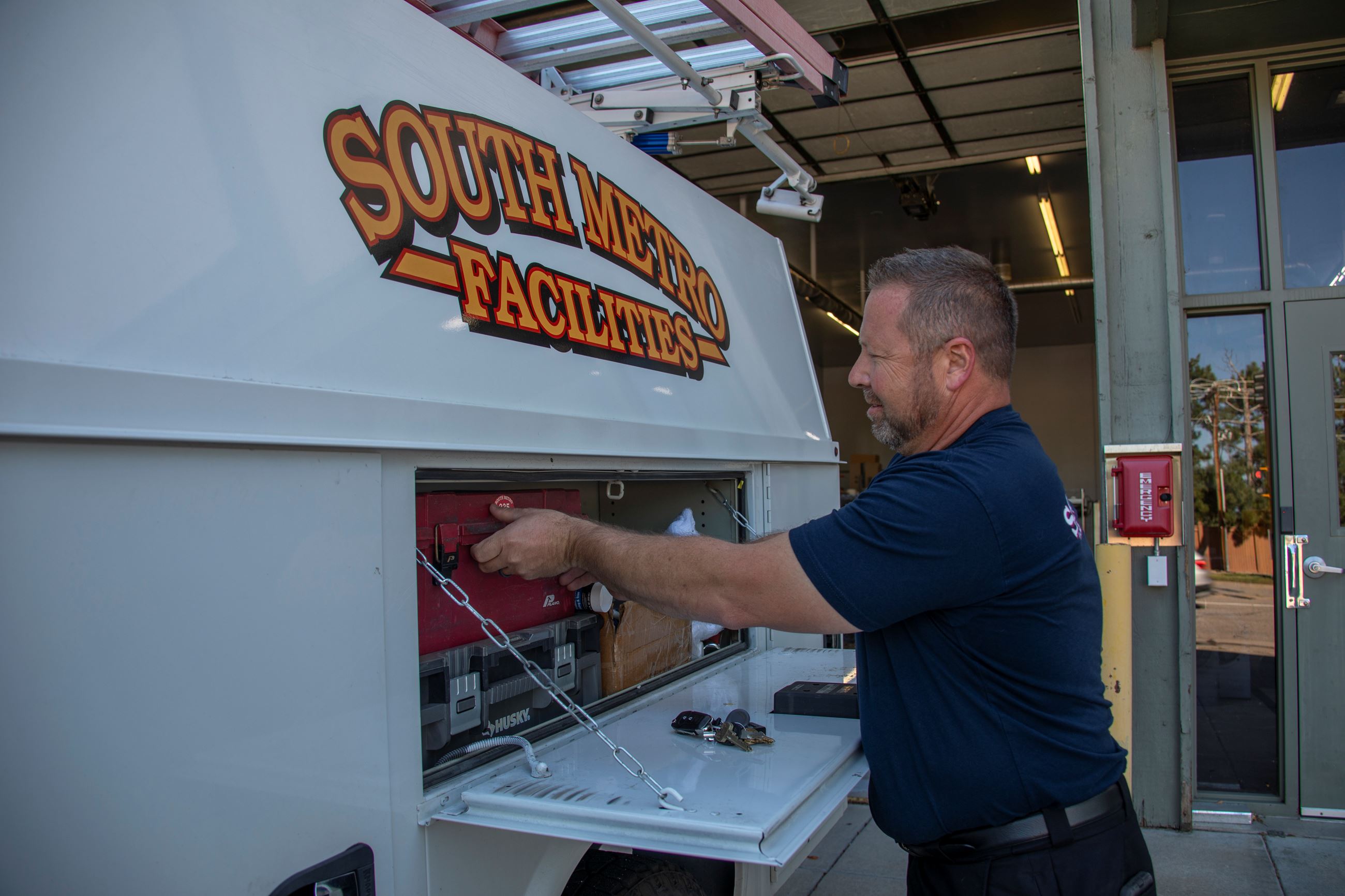 Facilities Worker Accessing a Tool Box in the Side of a Vehicle